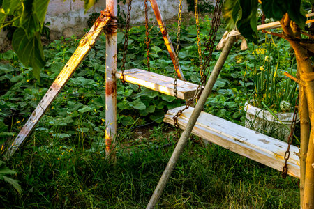 Rustic swing set amidst overgrown garden in the golden hour light, invoking nostalgia. high quality photoの写真素材