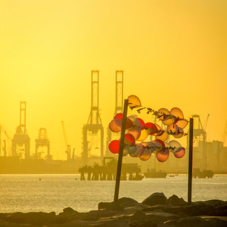 A striking scene of colorful balloons in front of an industrial sunset, reflecting the duality of hope amidst challenges and the pursuit of dreams in unlikely settings.の写真素材