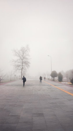 A foggy street with silhouettes of people walking, evoking a sense of mystery, solitude, and introspection in an abstract, atmospheric composition.の写真素材