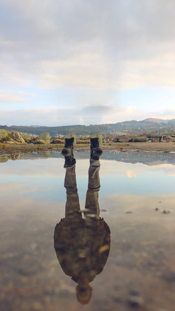 A unique image showing boots and the reflection of a man in water, symbolizing self-discovery,...