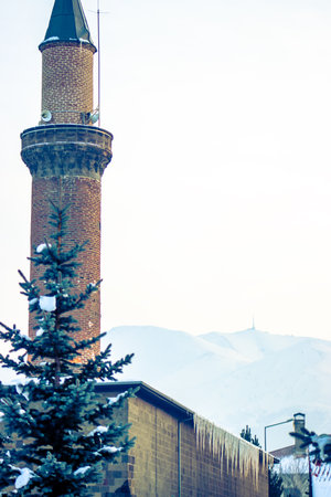 Erzurum Ulu Mosque minaret rises against the snowy Palandoken Mountain backdrop.の写真素材