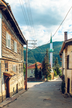 A serene view of an Ottoman-style street in Tarakli, Sakarya, Turkey, featuring traditional wooden houses and a mosque amidst lush greenery.の写真素材