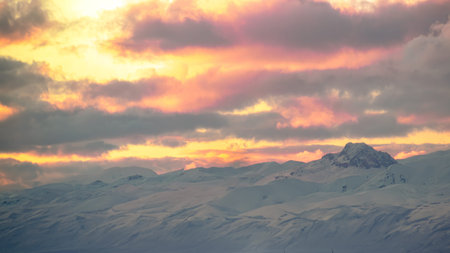 A peaceful winter landscape with distant mountains under a calm dramatic sky at sunset.
