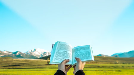 Book held up against nature, symbolizing enlightenment and knowledge.の写真素材