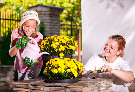 Mom and daughter planting flowers in potsの写真素材
