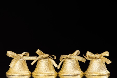 four golden bells on a mirror in front of a black background as a Christmas decorationの写真素材