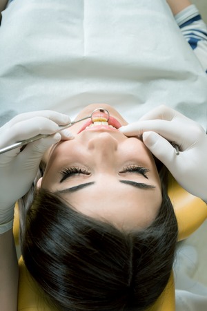 young women to the dentist in the dental chair sits next to a doctor to do the dentist to see if his teeth were okayの写真素材