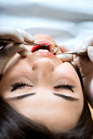 young women to the dentist in the dental chair sits next to a doctor to do the dentist to see if his...