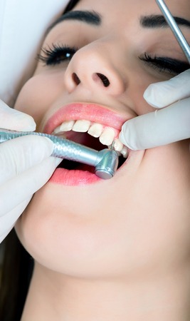 young women to the dentist in the dental chair sits next to a doctor to do the dentist to see if his teeth were okayの写真素材