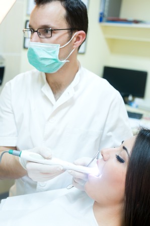 young women to the dentist in the dental chair sits next to a doctor to do the dentist to see if his teeth were okayの写真素材