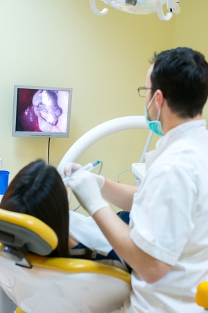 young women to the dentist in the dental chair sits next to a doctor to do the dentist to see if his teeth were okayの写真素材