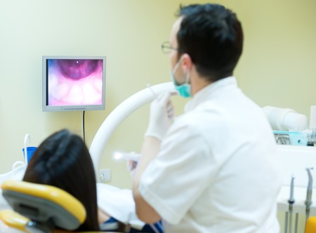 young women to the dentist in the dental chair sits next to a doctor to do the dentist to see if his teeth were okayの写真素材