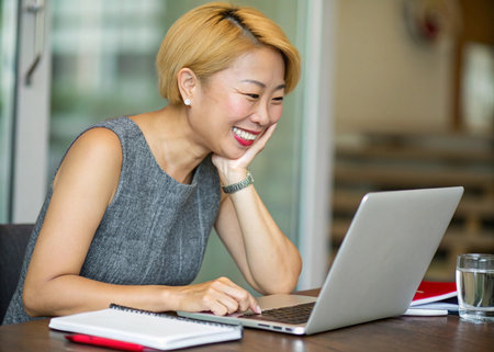 Happy asian businesswoman using laptop computer at her office desk.の素材