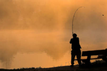 Fishing in foggy morning at sunrise. Soft filter was used.の写真素材