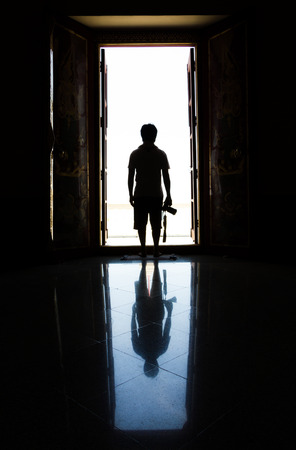 silhouette man in the door with cameraの写真素材