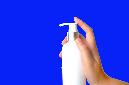 Woman hand presses a bottle of moisturizer on a white background.の写真素材