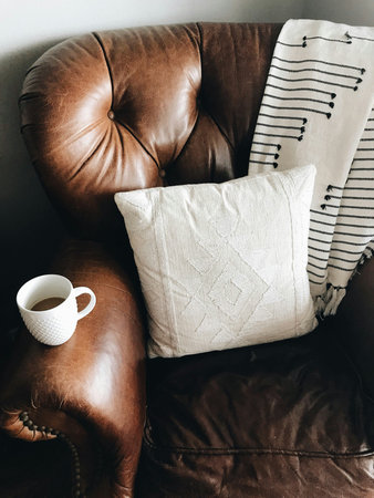 Coffee cup and pillow on brown leather sofa