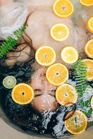 Beautiful young woman in a bath with oranges and lemons.の写真素材