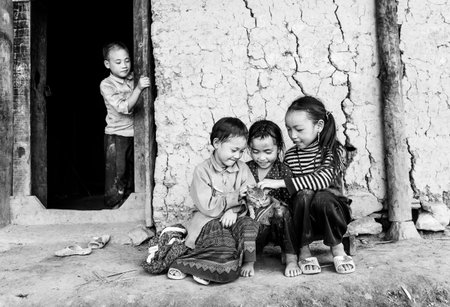 Lao Cai, Vietnam - September 27th, 2015: Ethnic boy watching his brother frolicking kids, play with the cat loves autumn afternoon in Lao Cai, Vietnamのeditorial素材