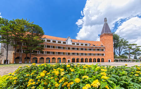 Da Lat, Lam Dong, Vietnam - May 23rd, 2015: arched architectural beauty, rustic buildings in Dalat Pedagogical University with red roofing tiles sunny impressive pines and benches inside school bold Da Lat city, Lam Dong, Vietnamのeditorial素材