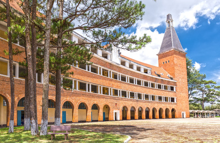 Da Lat, Lam Dong, Vietnam - May 23rd, 2015: arched architectural beauty, rustic buildings in Dalat Pedagogical University with red roofing tiles sunny impressive pines and benches inside school bold Da Lat city, Lam Dong, Vietnamのeditorial素材