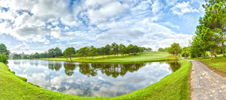 Panorama pine forest with beautiful lake on a still lake Reflected Reflected right is the path to shy green grass, forest, sky, clouds, water swirled together to create a beautiful picture in the highlands of Dalat, Vietnamの写真素材