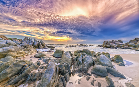 Dawn on the beach with brightly colored clouds, beneath a rock with beautiful scenery create beautiful shapes welcome fresh bright dayの写真素材