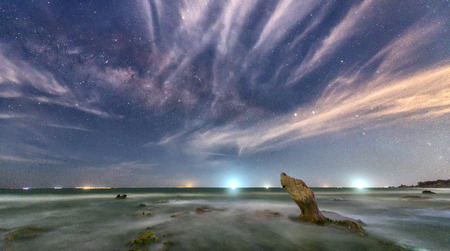 The beach at night with a rock towards the stars and sparkling galaxy create a great night scene to relax.の写真素材