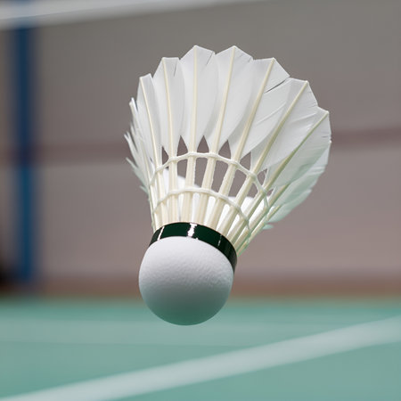 A white shuttlecock hovers above a green badminton court, ready for action in a fast paced game.の素材