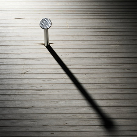 a close up of a nail hammered into wood, casting a long shadow. metal and wood texture design.の素材