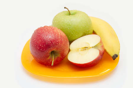 Red both green apples and banana on a yellow plateの写真素材