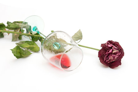 Red wine in a glass and a dried up roseの写真素材