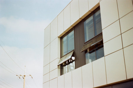 Contemporary architectural facade featuring geometric panels, large windows, and open window...