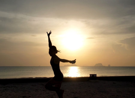 silhouette of a girl on the beach with sunsetの写真素材