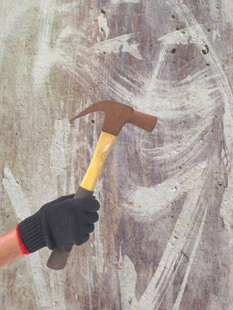 hammer in a hand with black glove on defected concrete panel background or textureの写真素材