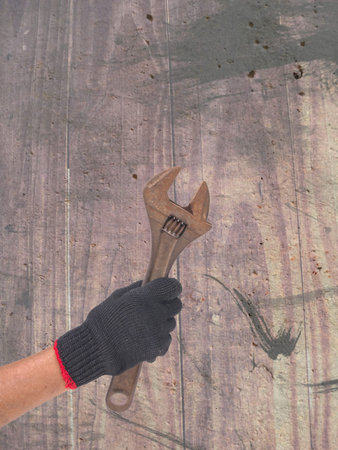 wrench in a hand with black glove on defected concrete panel background or textureの写真素材
