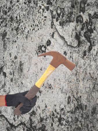hammer in a hand with black glove on defected concrete panel background or textureの写真素材