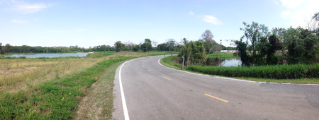 road between meadow roadsides with mountain background and clear sky look freedomの写真素材