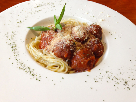 spaghetti meatballs with basil and parsley on white plateの写真素材