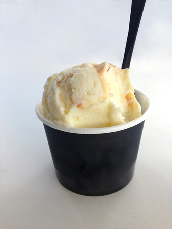 isolated black paper cup of ice cream with spoon on white backgroundの写真素材
