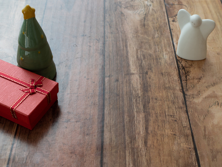 white angel, christmas tree and red gift for merry christmas background on wood plank with paper spaceの写真素材