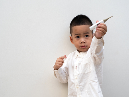 sick asian boy with thermometer in hand on white background and paper spaceの写真素材