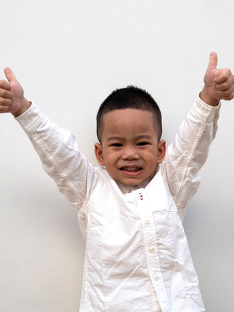 very happy asian boy making thumbs up sign and smiling happilyの写真素材