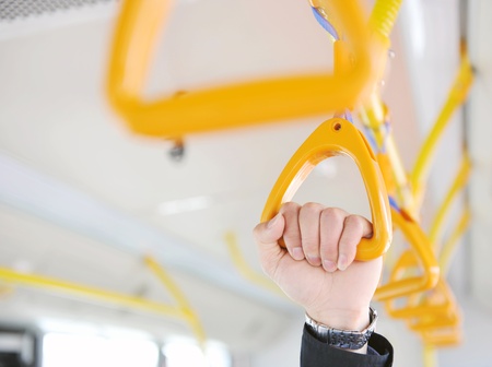 people holding onto a handle on a train.の写真素材