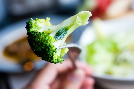broccoli in fork from plate of vegetable salad bowl.の写真素材