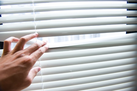 Men hands apart on the window blinds の写真素材