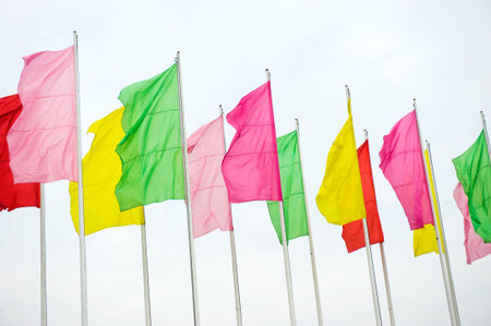 A row of colorful flags on masts waving in the wind,  isolated on white.