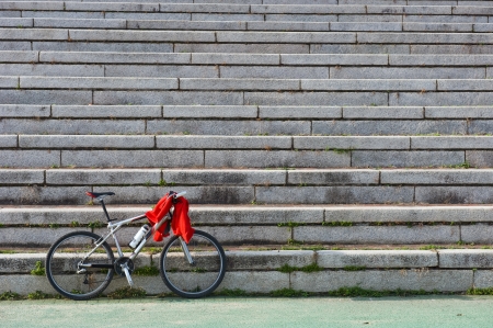 A bicycle leaning against the stone stairs, with a red clothes on it.の写真素材