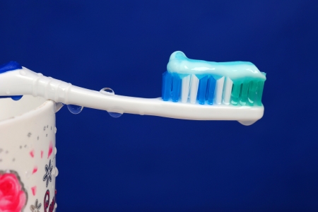A wet toothbrush with some toothpaste on it, and drops of water over blue background. 
の写真素材