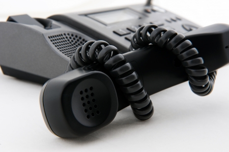 Black telephone receiver winded by telephone line.の写真素材
